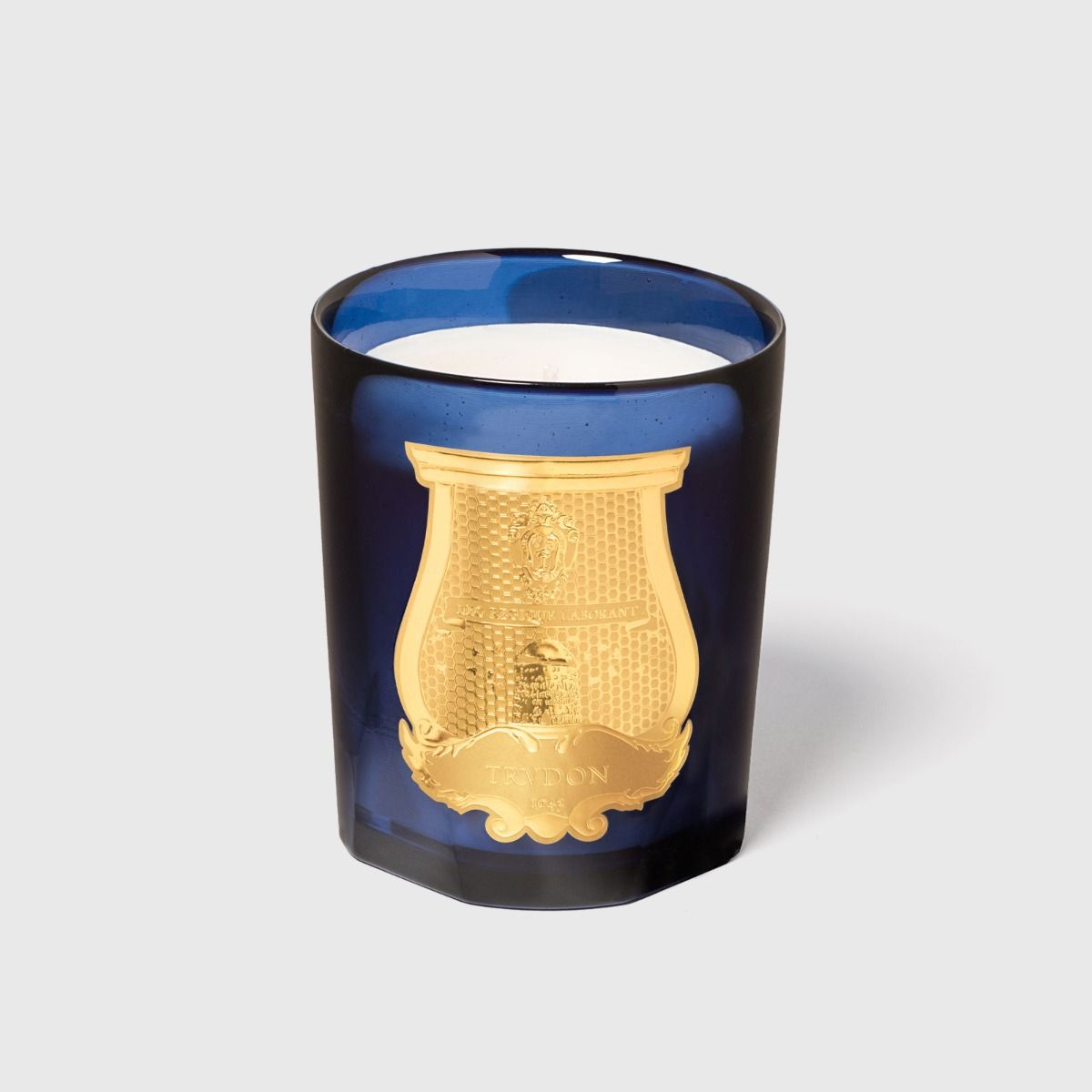 Trudon Reggio candle in blue glass jar with embossed gold crest emblem, front view