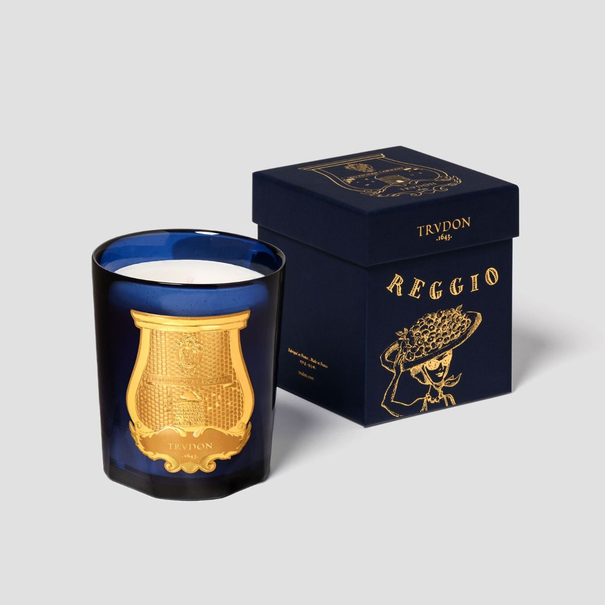 Trudon blue glass Classique candle beside its navy Reggio gift box with gold lettering