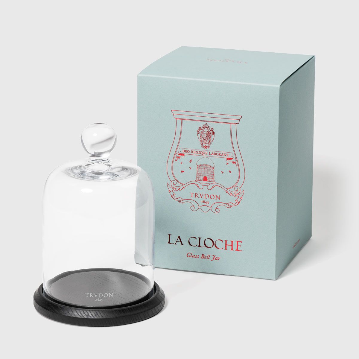 Trudon La Cloche glass bell jar with knob on black wood base, beside pale blue gift box
