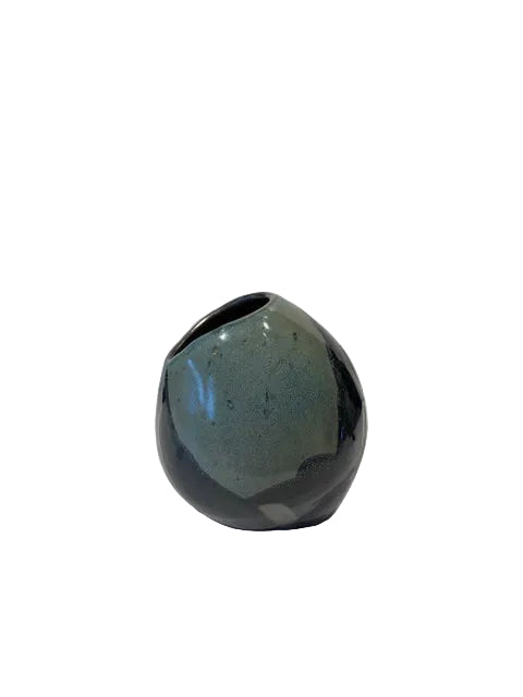 A small rounded ceramic vase with a glossy dark blue and green glaze, photographed on a white background with a soft shadow cast to the right.