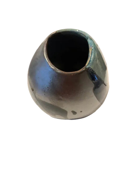 A small ceramic vase with a rounded bulbous shape and an open top, featuring a glossy glaze with blue, green, and dark brown tones, shown against a plain off-white background with a soft shadow.